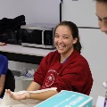 Students gathered around a table practicing clinical techniques with medical supplies and sample materials during an interactive training session.